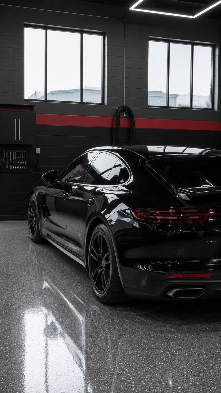 Black Porsche Panamera after polishing, rear three-quarter view under studio lights.