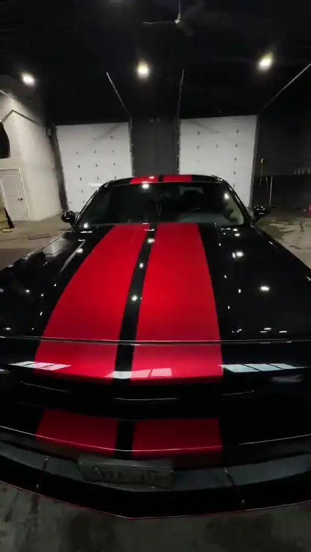 Black Dodge Challenger with red stripes after paint correction, second angle.