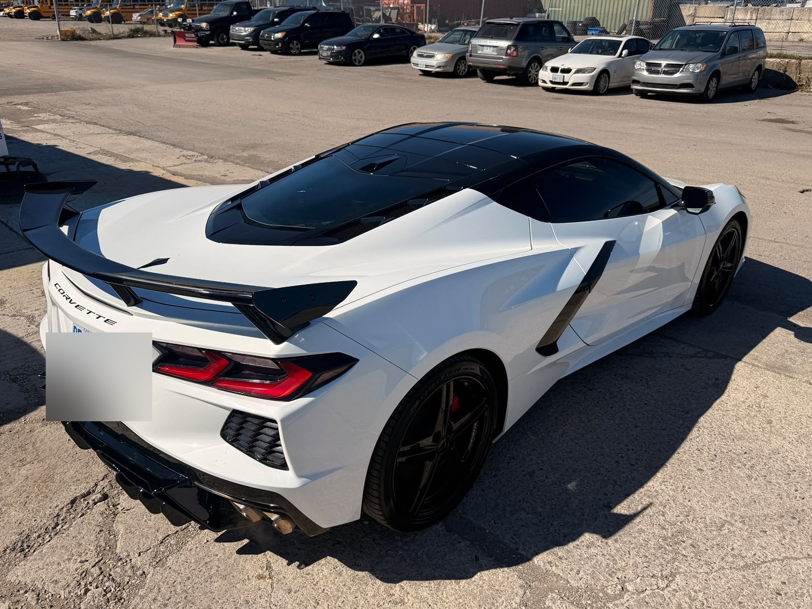 White Chevrolet Corvette C8 rear view after PPF wrap, window tint and rear diffuser install. Plate blurred for privacy.