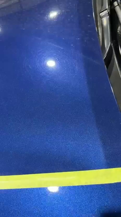 Blue car hood with a taped square test area: one-step machine correction inside the tape, uncorrected paint outside it.