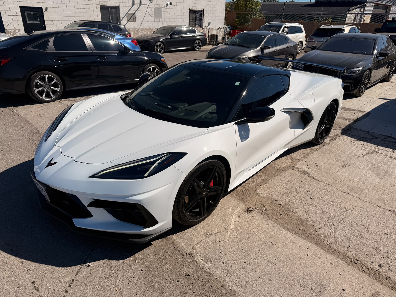 White Chevrolet Corvette C8 after a full PPF wrap, window tint and rear diffuser install, front three-quarter view.