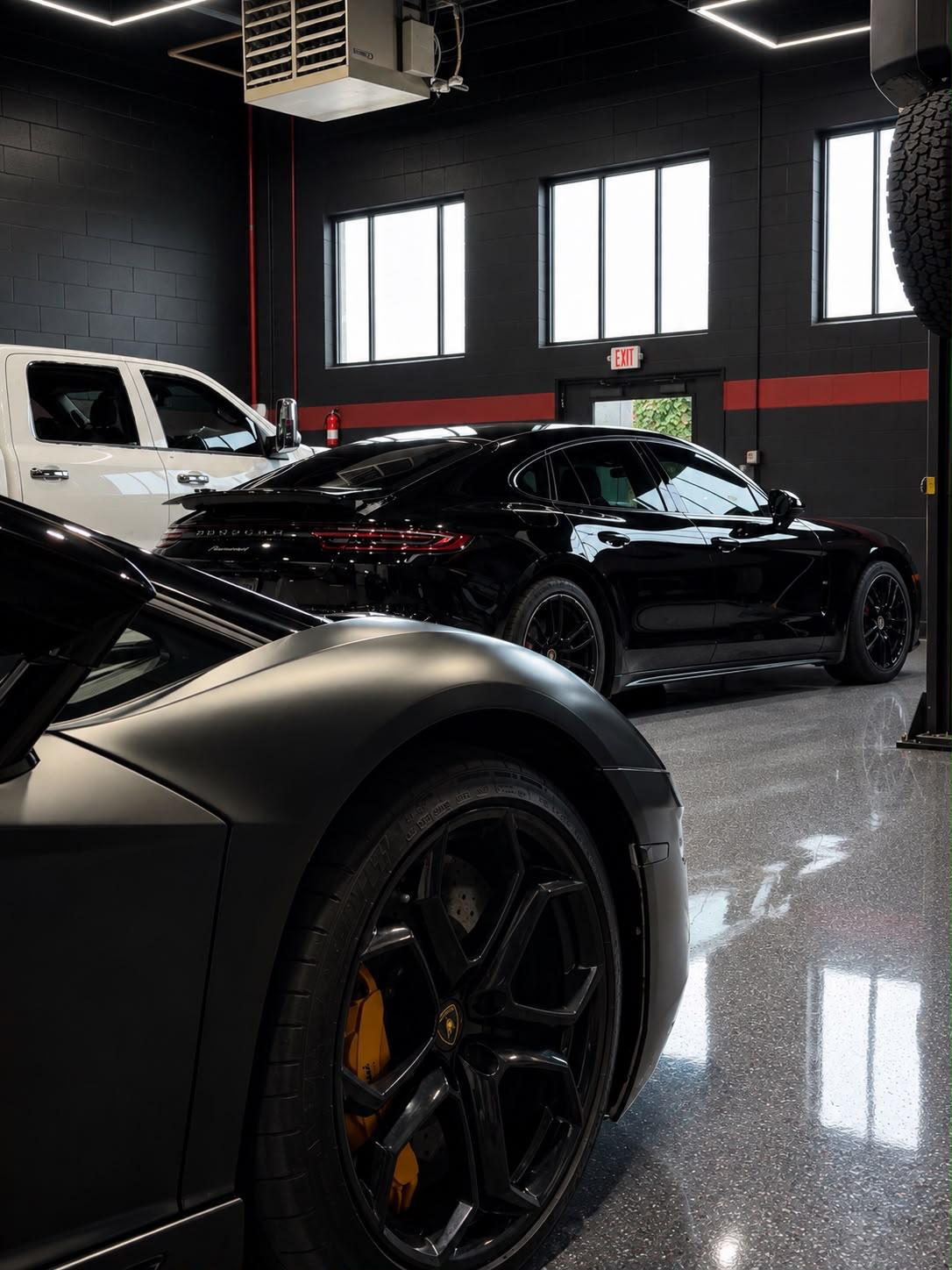 Black Porsche Panamera in the studio after polishing, with another car in the foreground.